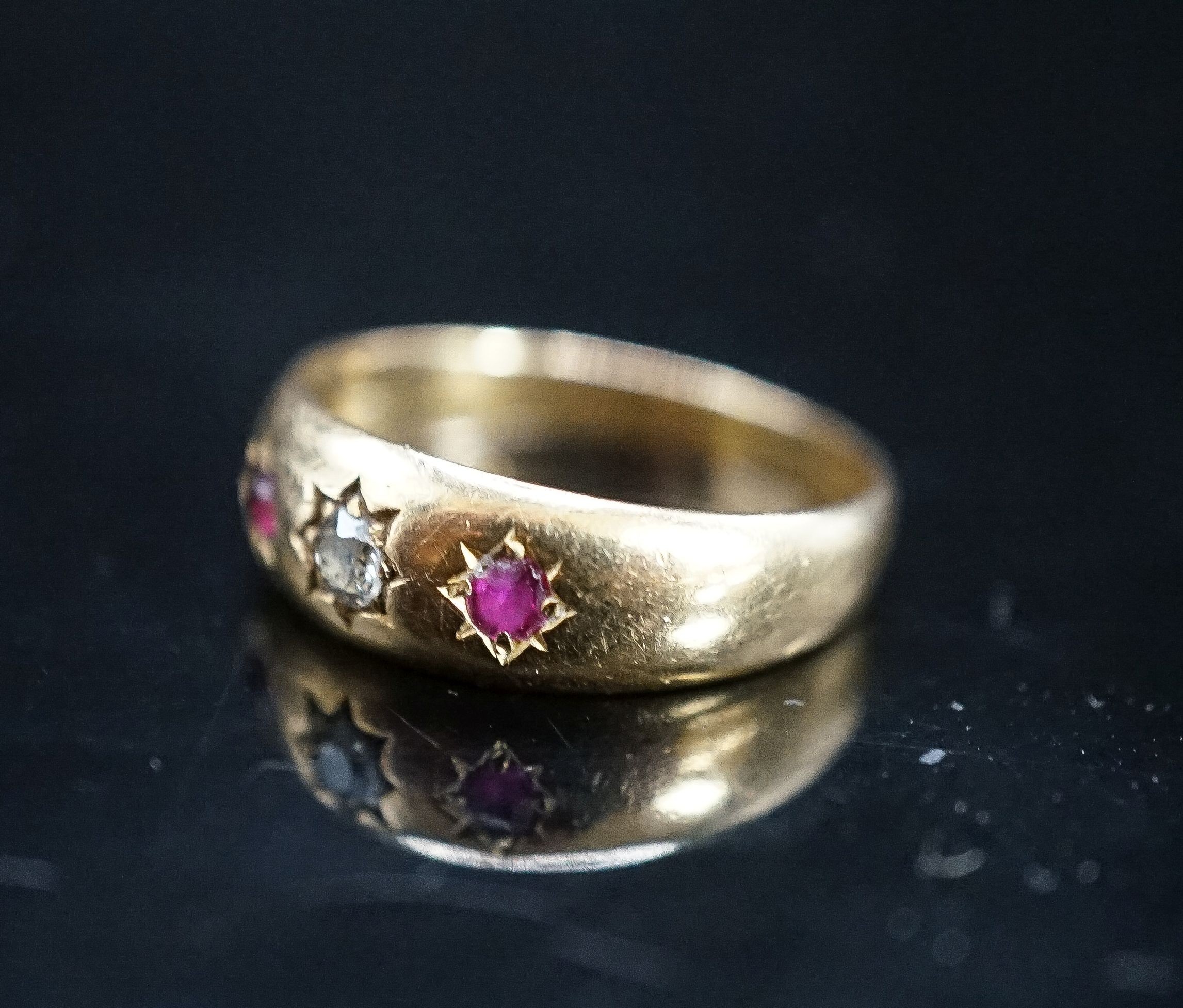An early 20th century yellow metal and gypsy set ruby and diamond set three stone ring, size O, gross 3.9 grams.